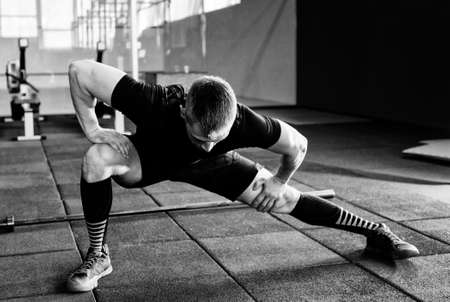 Young man preparing muscles before training. Muscular athlete exercising. Fit man stretching. Professional sportsman warming-upの写真素材