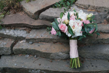 Beautiful wedding bouquet of white and pink peony and roses in natural stone in blur outdoors, close up, free spaceの写真素材