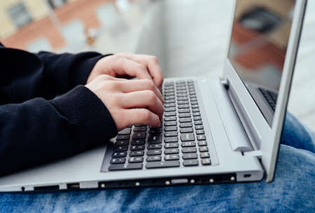 Side view of man's hands typing on laptop computer outdoors, Closeup. Technology and communication conceptの写真素材