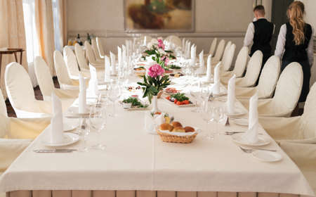 Table served for wedding banquet, selective focus. Pink peonies in vases on dinner table. Table setting. Peony on dinner table for wedding banquetの写真素材
