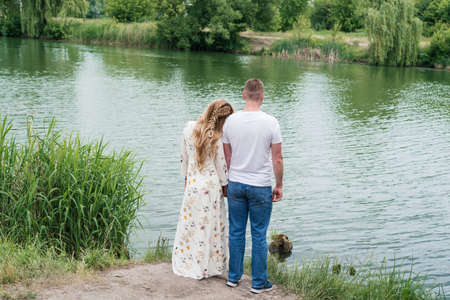 Couple in love walking and hugging on the river bank outdoors, back view. Free spaceの写真素材