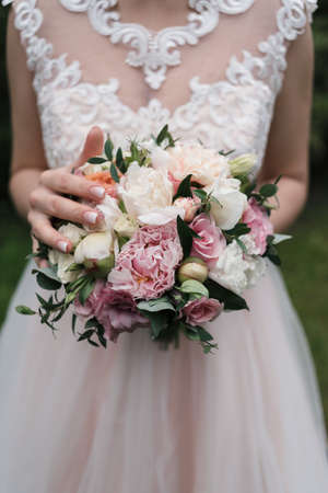 Lush wedding bouquet of white and pink peonies, roses and greenery in the bride's hands. Bride with wedding bouquet の写真素材