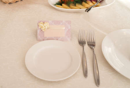 Blank card for guests near white empty plate on dinner table for wedding banquet, free space for textの写真素材