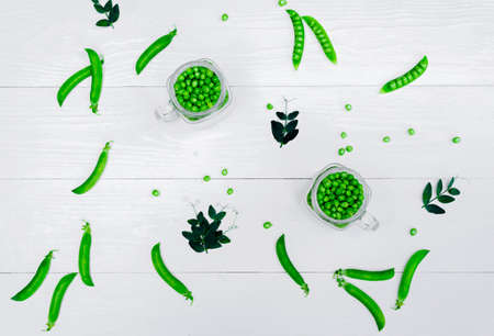 Full glass jar with fresh green peas on white wooden background, top view. Bio healthy food. Green peas in jar, pods and pea leaves on wooden tableの写真素材