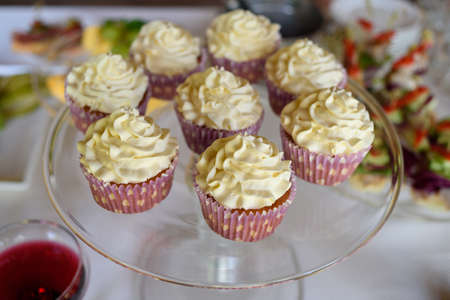 Candy bar served with cupcakes with vanilla cream on glass stand, selective focus. Holiday candy barの写真素材