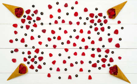 Top view of sweet fresh organic raspberries and blackberries in waffle cones. Fresh berries in cones on white wooden background with. Summer and healthy food concept flat layの写真素材