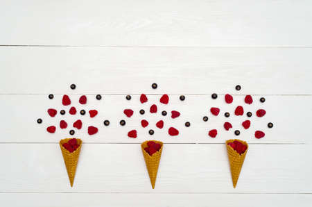 Top view of sweet fresh organic raspberries and blackberries in waffle cones, free space. Fresh berries in cones on white wooden background with blank space. Summer and healthy food concept flat layの写真素材
