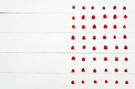 Top view of lines from sweet fresh organic raspberries, free space. Fresh berries on white wooden background with blank space. Summer and healthy food concept flat layの写真素材