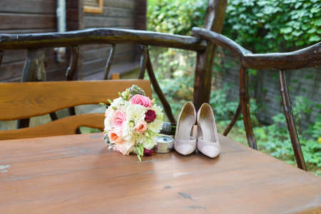 Fresh wedding bouquet, box with rings and  beige shoes stand on wooden table outdoor, free space.  Wedding details with copy space. Wedding morning preparationの写真素材