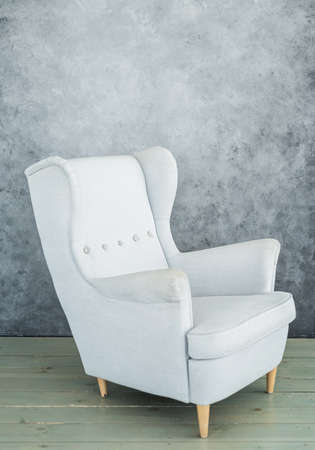 One soft gray velvet armchair near gray wallの写真素材