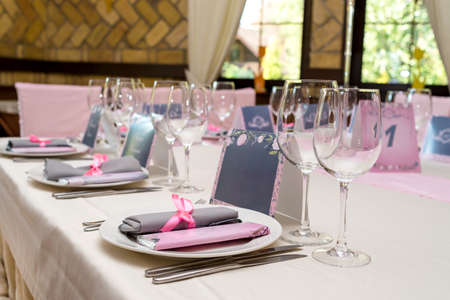 Rolled gray table napkin with pink ribbon and bar of chocolate with blank space for text on white empty plate. Table setting, free space. Table served for wedding banquet. Paper blank cards for guestsの写真素材