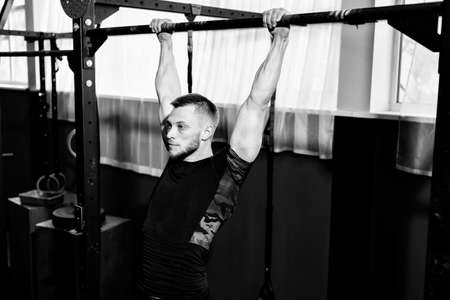Muscular bearded man training his biceps and back in gym. Pull-ups. Workout lifestyle concept