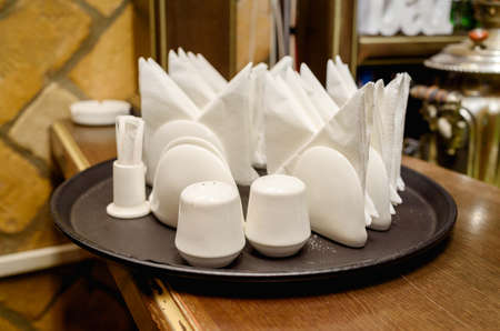 White pepper and salt shakers with napkin holders on tray, selective focus. Cafe table top set with...