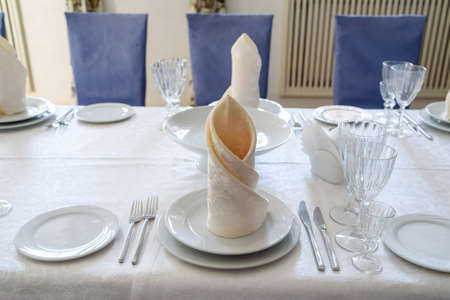 Table with white plate, crystal wineglasses, linen beige napkin and cutlery on tablecloths, free...