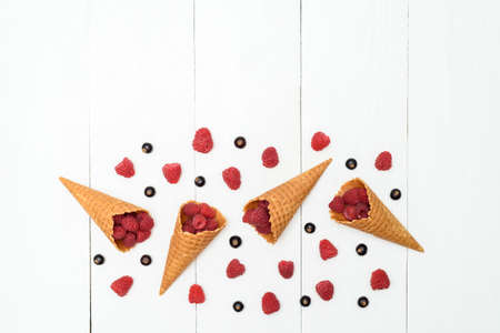 Top view of sweet fresh organic raspberries and blackcurrants in waffle cones, free space. Fresh...