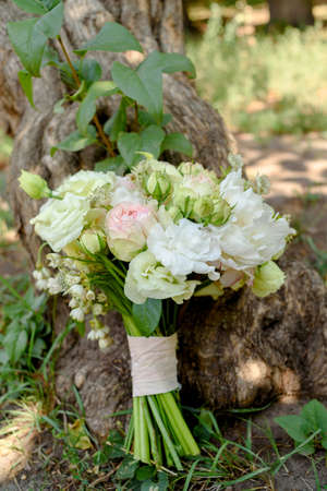 Beautiful wedding bouquet of fresh white and pink roses and peonies standing under tree outdoors. Bridal bouquet, close upの写真素材