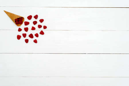 Top view of sweet fresh organic raspberries in waffle cone with free blank space. Fresh berries in cone on white wooden background. Summer and healthy food concept. Berries backgroundの写真素材