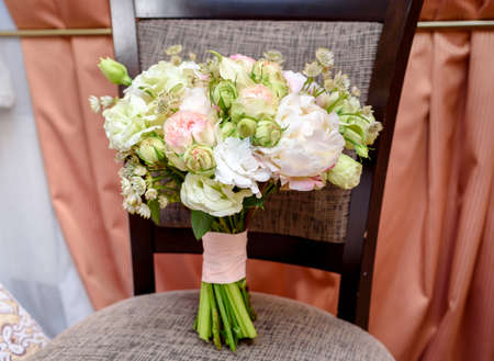 Beautiful wedding bouquet of fresh white and pink roses standing on chair near the window indoors, free space. Bridal bouquet, close upの写真素材