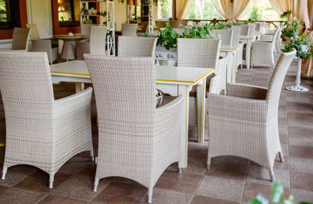 Empty cafe with rattan wicker armchairs and tables on summer garden terrace outdoor, free space. Table and chairs in empty cafe. Wicker furniture rattan chairs on terrace  の写真素材