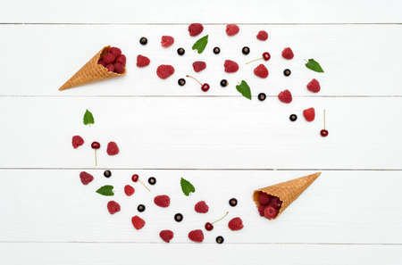 Frame from sweet fresh raspberries, cherries and black currants in waffle cone, free space. Fresh berries in cones. Summer, healthy food concept, flat lay, top view. Berries background. Mix of berriesの写真素材