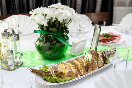 Stuffed sliced pike with salad on dinner table, selective focus. Stuffed pike fish with lettuce leaves, tomato and slices of lemonの写真素材