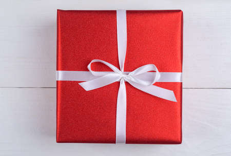 Red gift box with white ribbon on wooden background. Holiday greeting card. Mothers day, birthday, Women's Day, mum's day, Valentine's day, Christmas, Wedding, Anniversary, 8 March. Top view, flat layの写真素材