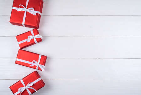 Red gift boxes with white ribbon on white wooden background, copy space. Holiday greeting card. Mothers day, birthday, Women's Day, mum's day, Valentine's day, Christmas, Wedding. Top view, flat layの写真素材