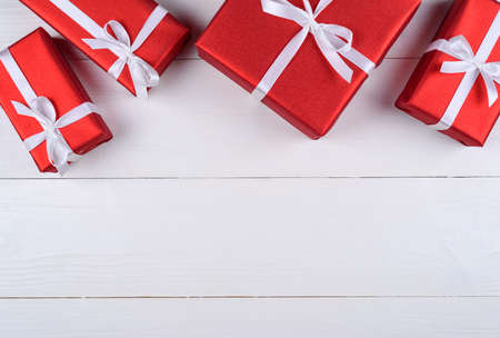Red gift boxes with white ribbon on white wooden background, copy space. Holiday greeting card. Mothers day, birthday, Women's Day, mum's day, Valentine's day, Christmas, Wedding. Top view, flat layの写真素材