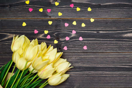 Spring background with bunch of yellow tulip flowers and pink heart sprinkles, copy space. Flat lay, top view. Holiday greeting card for Valentine's Day, Woman's Day (March 8), Mother's Day, Easterの写真素材