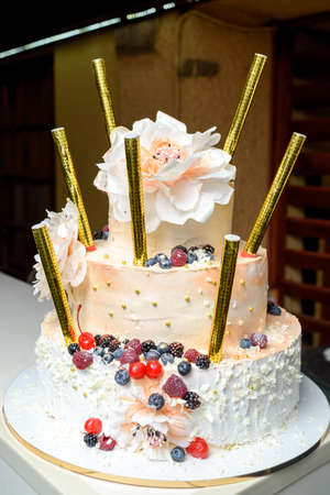 White multi level birthday or wedding cake with flowers, berries and bengal firesの写真素材