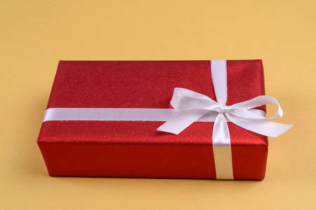 Red gift box with ribbon and bow on golden background, copy space. Holiday greeting card. Mothers day, birthday, Women's Day, mum's day, Valentine's day, Christmas, Wedding, Anniversary, 8 Marchの写真素材