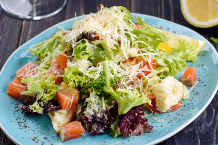 Fresh smoked salmon salad with lettuce leaves, parmesan cheese and rusks served with lemon slice, close up. Healthy foodの写真素材