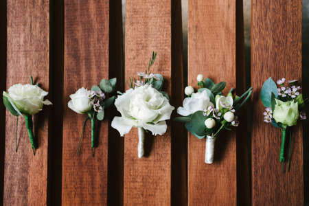 Top view of wedding boutonniere for the groom and bridesmaids on wooden background, free space. Wedding details outdoor with copy space. Wedding morning preparationの写真素材