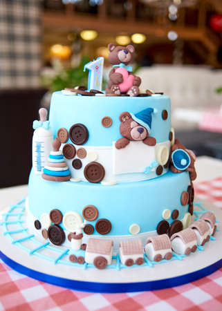 Round multi tiered blue  birthday cake decorated with button, toys, bears, locomotive and number one on the top, copy space for textの写真素材