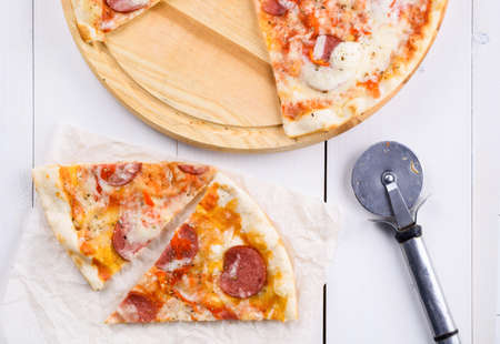 Hot sliced classic pepperoni pizza on wooden board, close up. Fresh pizza with pepperoni, mozzarella and tomato sauce, copy space. Italian traditional cuisine, foodの写真素材