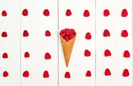 Top view of one waffle cone with sweet organic raspberries between raspberry rows, free space. Fresh berries in cone on wooden background. Summer, healthy food concept, flat lay. Berries backgroundの写真素材