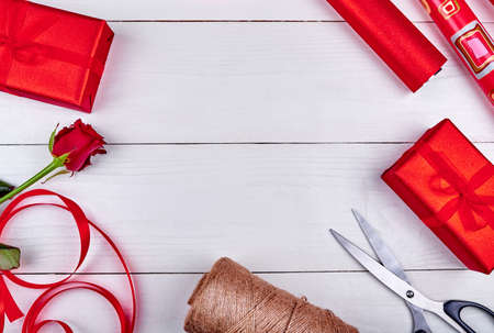 Gift wrapping background, copy space. Rolls of wrapping paper, ribbon, one red rose, gift boxes and scissors on wooden background. Flat lay, top view. Valentines Day, Womens Day (March 8), Mothers Dayの写真素材