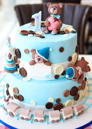 Round multi tiered blue  birthday cake decorated with button, toys, bears, locomotive and number one on the top, copy space for textの写真素材