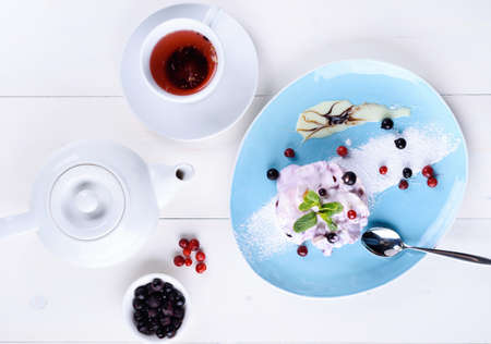 French gourmet mille feuille with whipped sour cream and mint leaf on plate and berry tea in white cup. Millefeuille dessert. Sweet cake with berries. Top view, flat layの写真素材