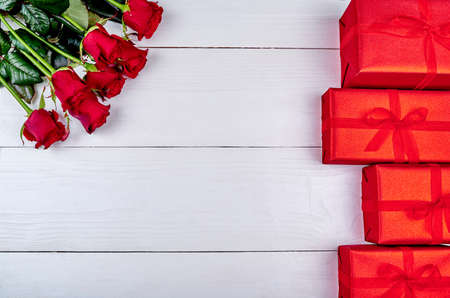 Bouquet of red roses and gift boxes on white wooden background, copy space. Greeting card mockup for Saint Valentines Day, Womens Day (March 8), Mothers Day. Top view, flat lay. Love conceptの写真素材