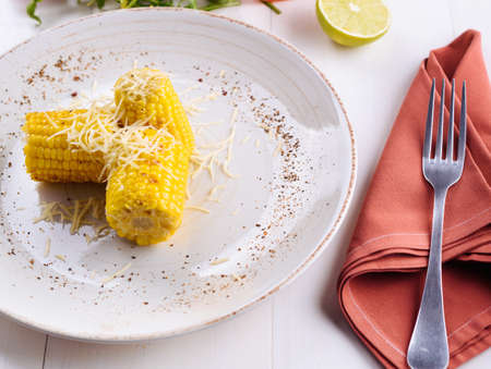 Delicious grilled corn with salt, butter and parmesan cheese ready to eat on white plate, copy space. Roasted corn on cob. Healhty food. Summer food for barbecue (bbq) and grill partiesの写真素材
