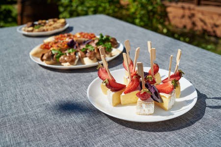 Canape with camembert cheese brie and strawberry on white plate, copy space. summer holiday reception outdoors. Buffet. Fruits and cheese on plateの写真素材