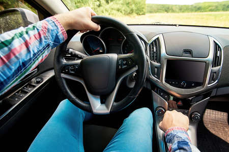 Close up of steering wheel in male driver hand, copy space. Man's hand holding steering wheel inside carの写真素材
