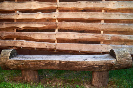 Wooden rough bench against wood plank wall outdoor, copy space. Empty wooden bench made of logs. Lonely placeの写真素材