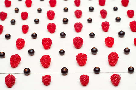 Rows of ripe sweet raspberries and black currant, free space. Fresh berries on white wooden background. Summer, healthy food concept. Berries backgroundの写真素材