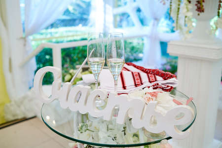 Two wedding glasses of champagne (sparkling wine) and word "Happiness" in russian on glass table on wedding ceremony. Sign Happiness made from white wooden letters, copy spaceの写真素材