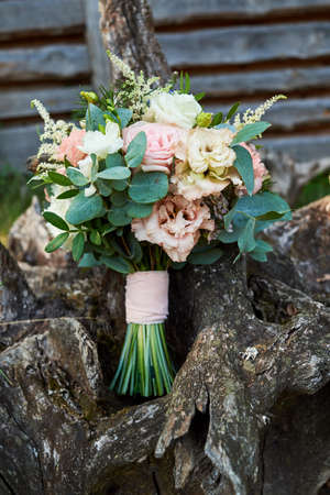 Beautiful wedding bouquet of fresh white and pink roses, blue flowers and greenery standing on wood stump outdoors, free space. Bridal bouquet, close upの写真素材