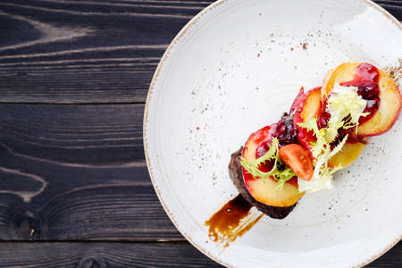 Grilled goose liver (foie gras) with sweet berry sauce and caramelized apples in white plate on table, copy space. French cuisine, delicatessen restaurant meal. Top view, flat layの写真素材