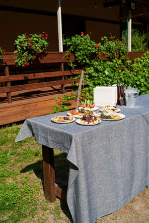 Delicious snacks, appetizers, sandwiches on party or picnic table. Holiday summer party table outdoor in garden. Catering banquet table with different food snacks on birthday or wedding celebrationの写真素材