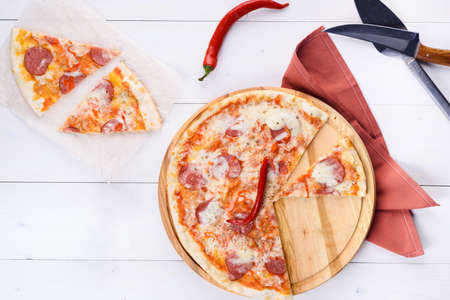 Hot sliced classic pepperoni pizza on wooden board, copy space. Fresh pizza with pepperoni, mozzarella and tomato sauce, copy space. Italian traditional cuisine, food. Top view, flat layの写真素材